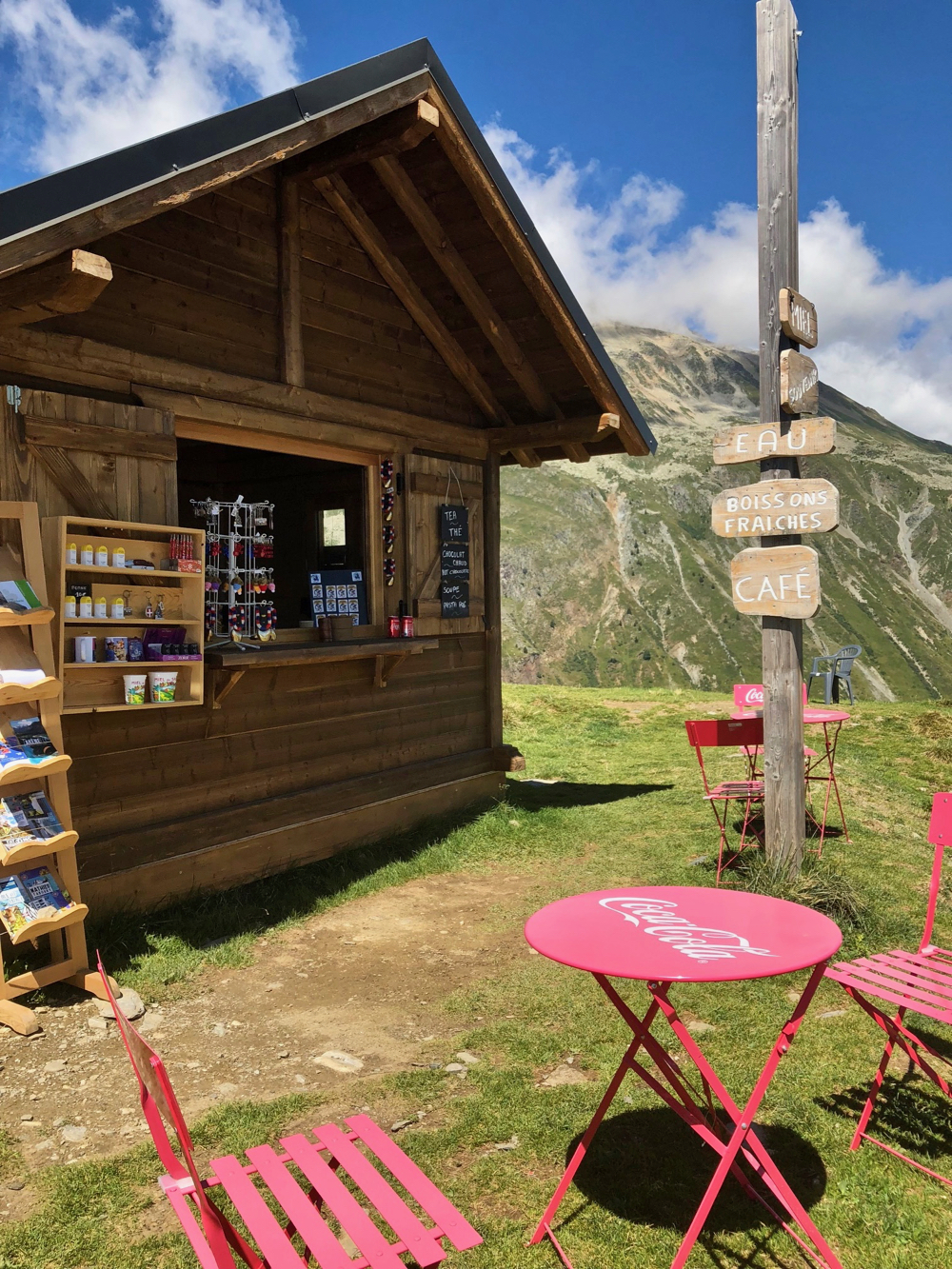 Rode coca cola stoeltjes voor een houten hutje waar je iets te drinken kunt kopen. Hoog in de bergen.