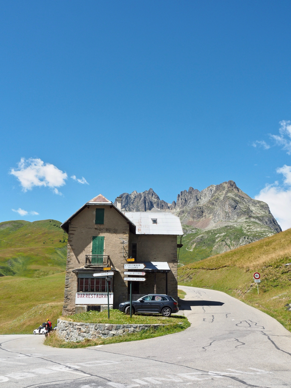 Stenen huis met groene luiken op een splitsing van twee bergwegen