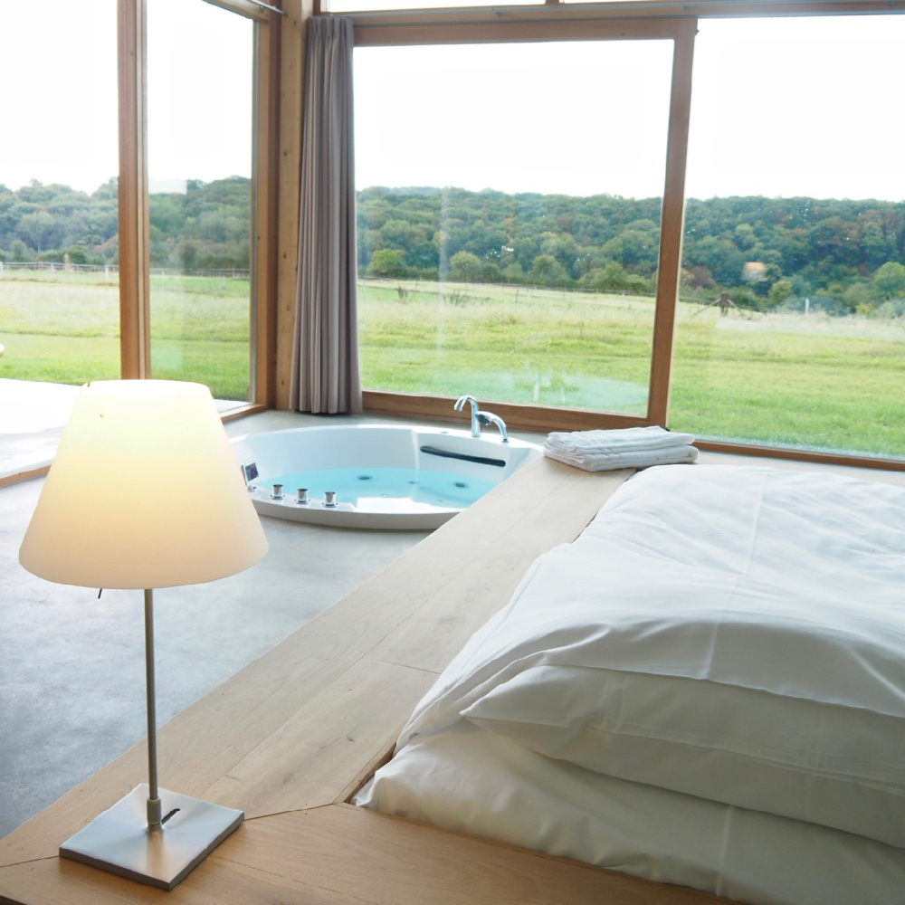 Een grote glazen gevel met een bed en bad voor het raam