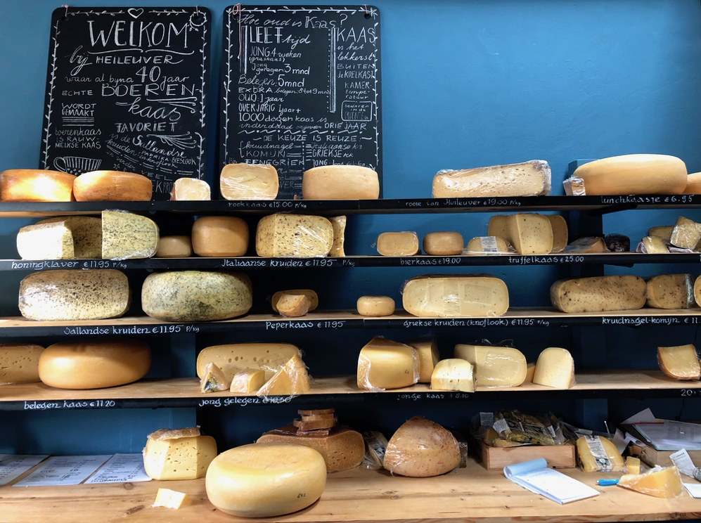 De toonbank in de kaaswinkel met planken met kaas en een blauwe achterwand