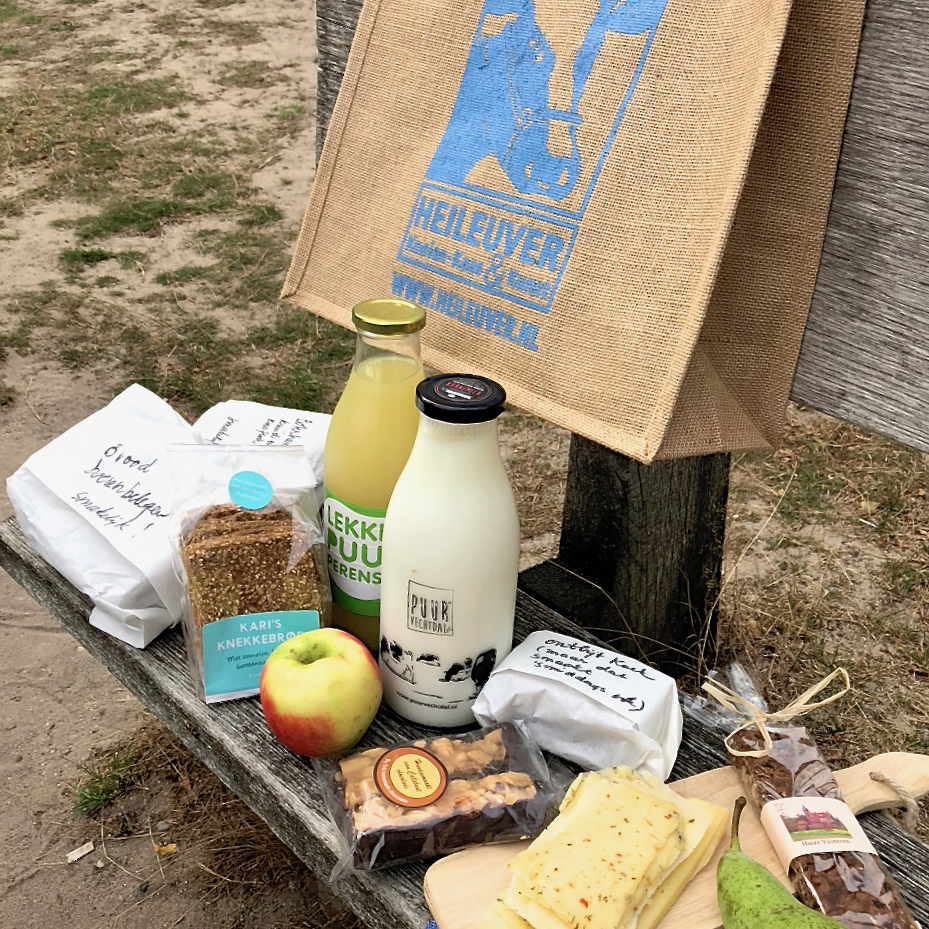 Picknick op een bankje, met verse melk en sap, brood, kaas, appels en lekkere crackers.