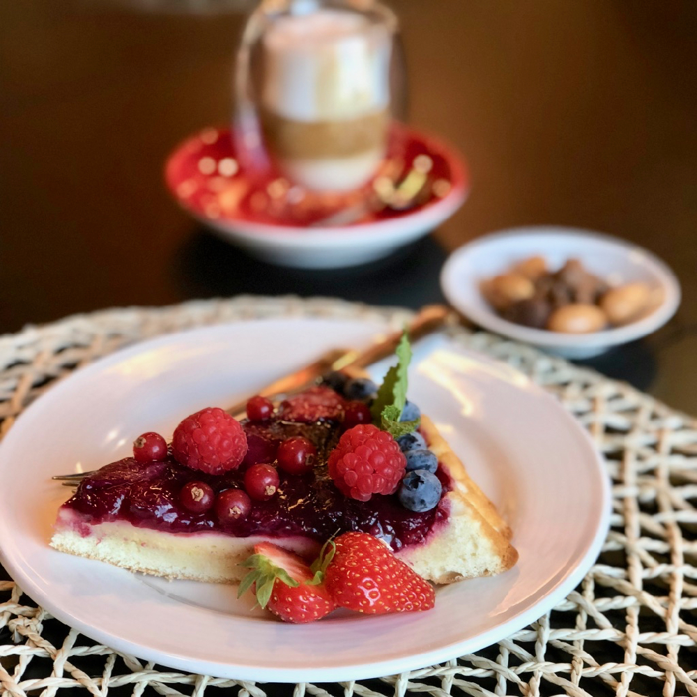 Een taart met rood fruit en een cappuccino