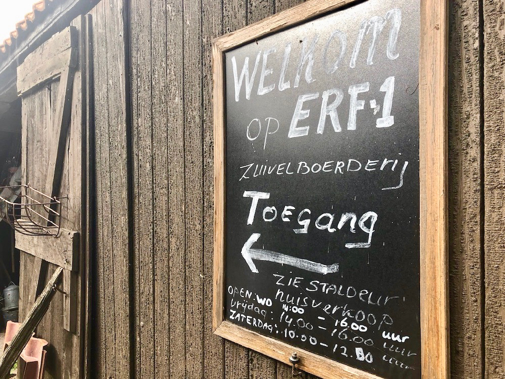 Welkom bij Erf 1: een krijtbord met tekst op de schuur van de boerderij