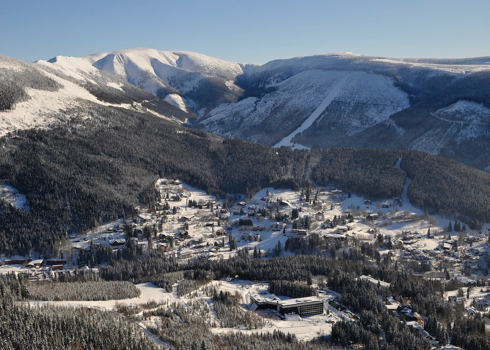 Een zicht op een dorp in een dal, tussen de dennenbomen en pistes, in de winter