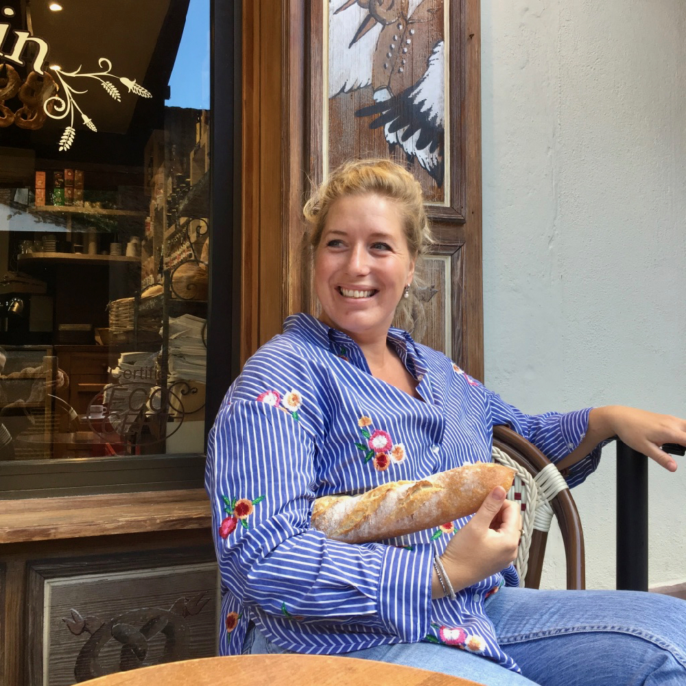 Jorieke op een terras in de Elzas, met een stokbrood onder haar arm