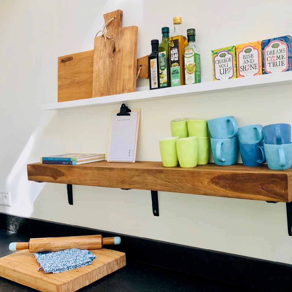 Schappen aan de muur met houten planken, mokken en thee
