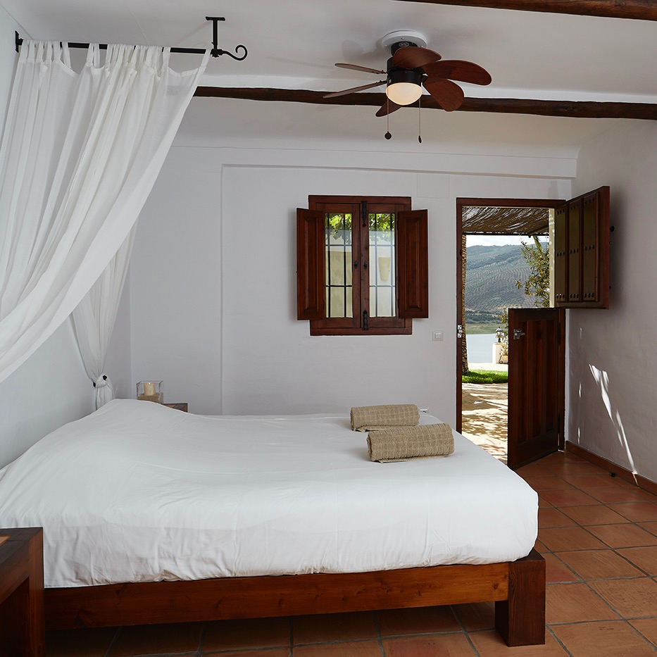 Tweepersoons bed met klamboe en deur naar buiten
