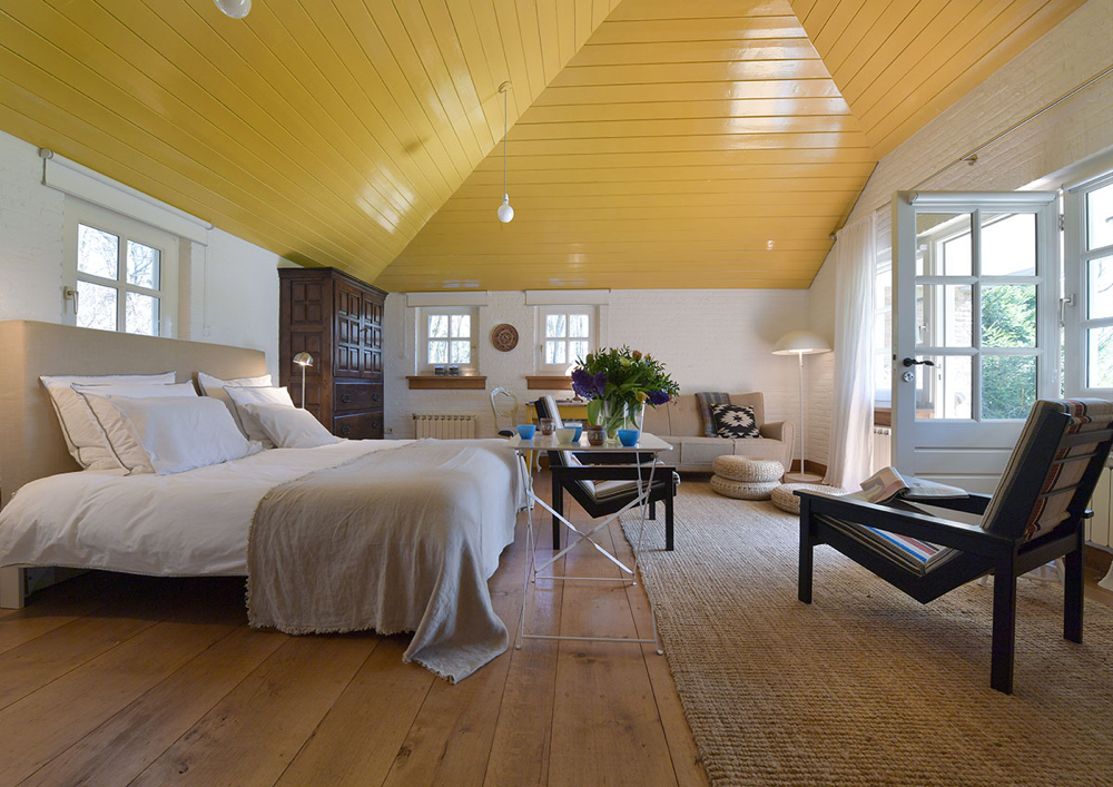 Tweepersoons bed met zithoek, openslaande deur en geel houten plafond