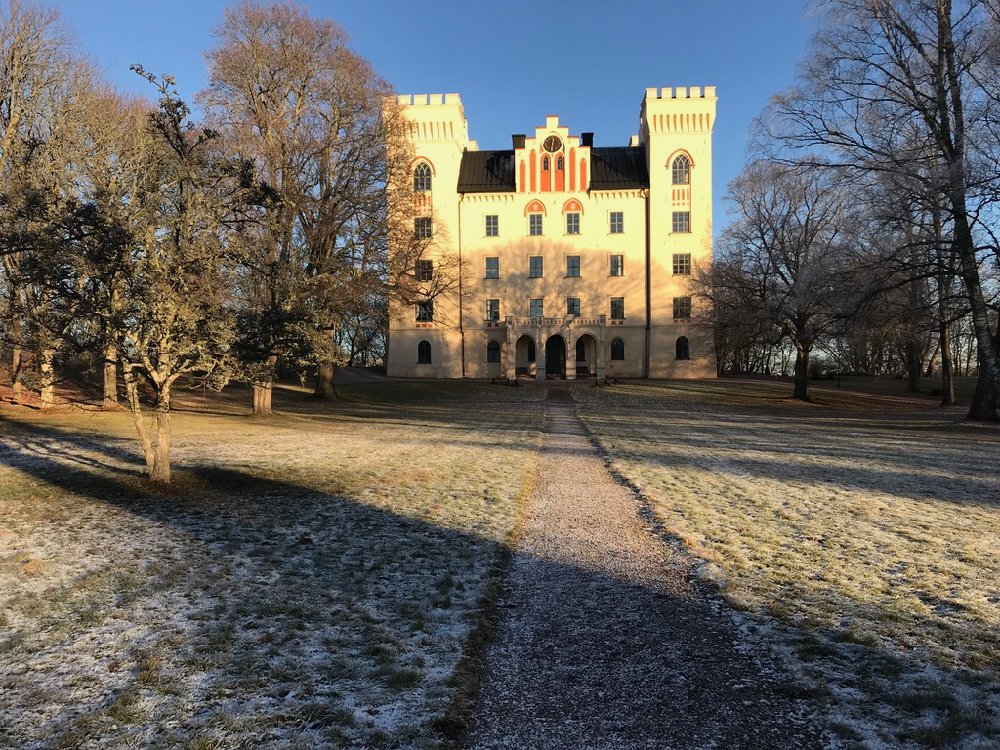Een bevroren oprijlaan met een geel kasteel met twee torens