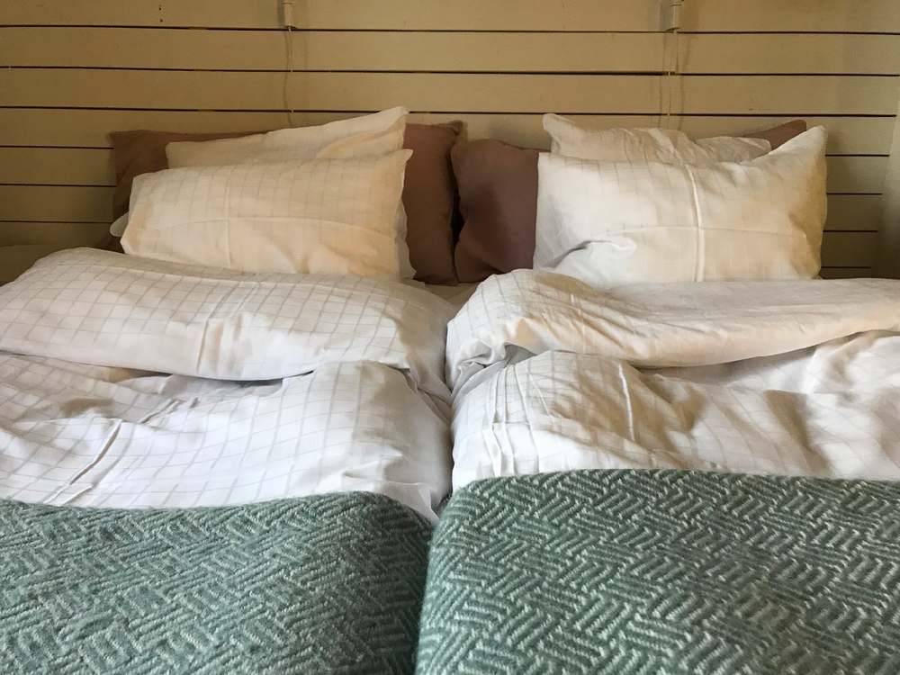 Een tweepersoons bed met groene warme deken en wit beddengoed