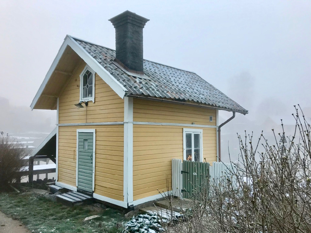 Een geel houten huisje op het Zweedse eiland Vaxholm, met een laagje rijp bedekt. 