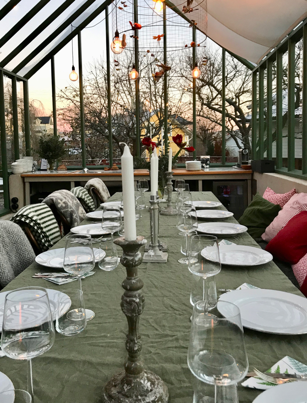 Een gedekte tafel in een kas met kaarsen, in de tuin van Vaxholms B&B