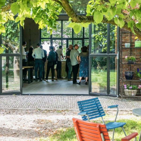 Schuur met opengeslagen metalen deuren, groep mensen aan het borrelen