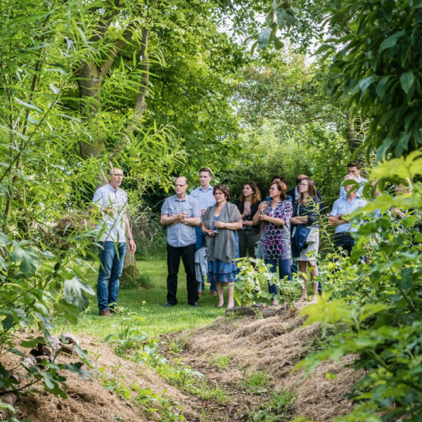 Een groep mensen krijgt een rondleiding door het voedselbos