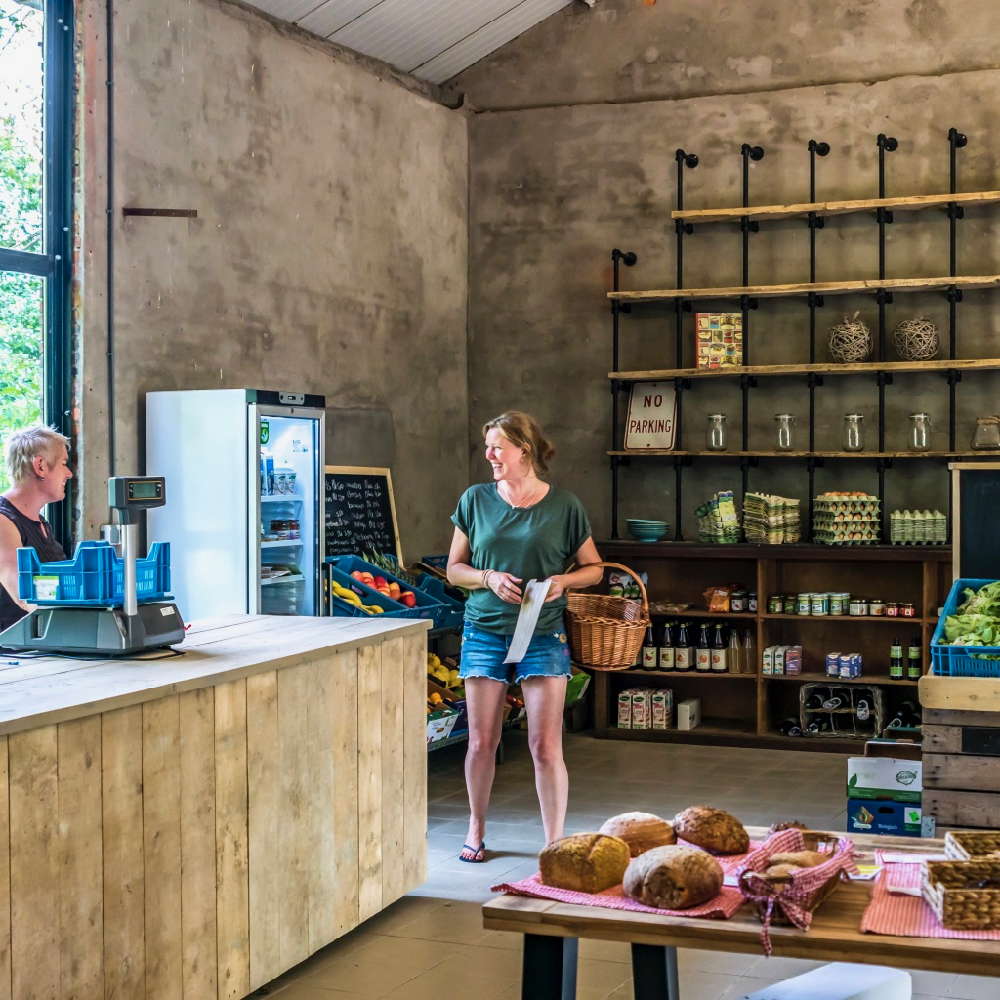 Winkel met steigerhouten toonbank, broden en stoere schappen langs de muur