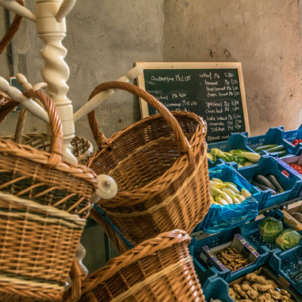 Rieten manden aan een kapstok, groente in blauwe bakken