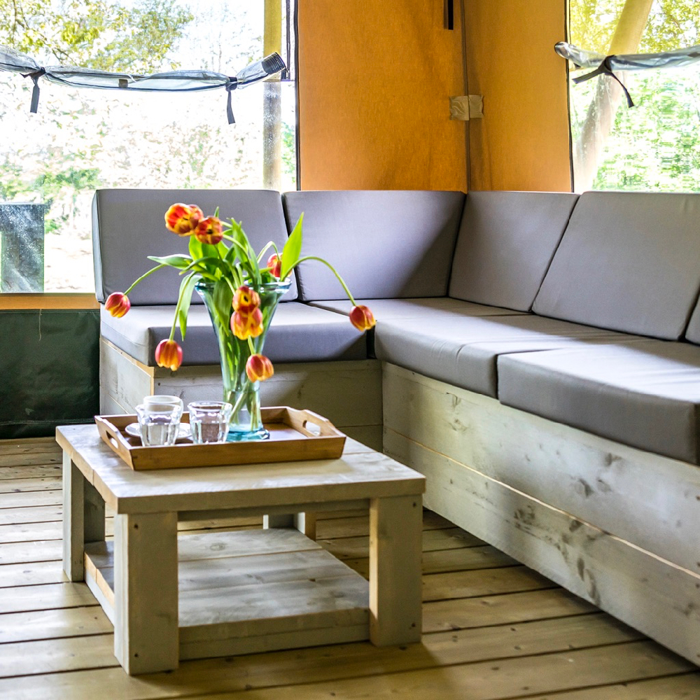 Loungebank met grijze kussens en een tafel met bos tulpen