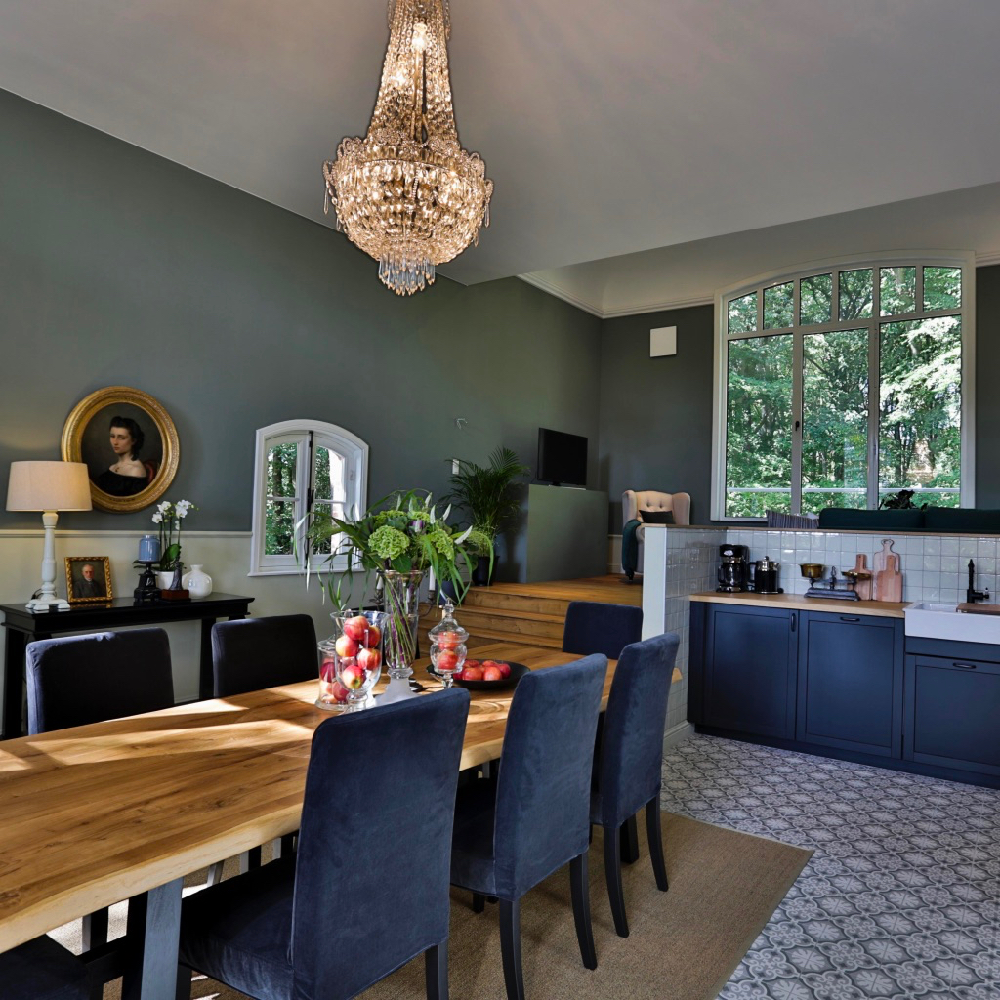 Eettafel met kroonluchter erboven en keuken met antraciet deurtjes