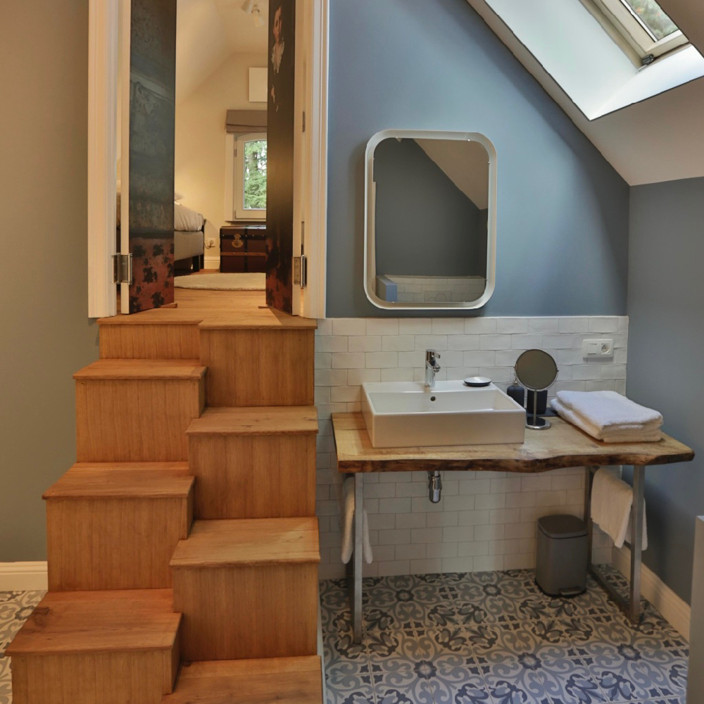 Badkamer met lichtlbauw grijze muur, houten trap naar slaapkamer