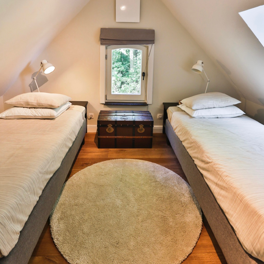 Slaapkamer met twee aparte bedden, onder een schuin dak