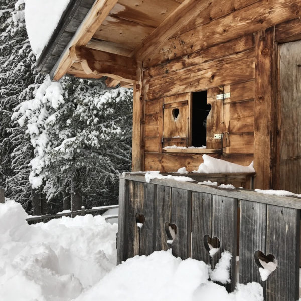 Houten hut met hartjes in de luiken in de sneeuw