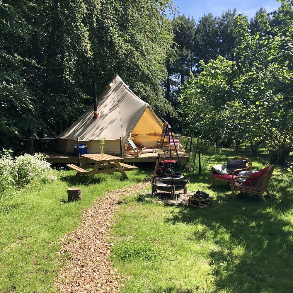 Openstaande Bell tent op houten vlonder met twee stoeltjes ervoor