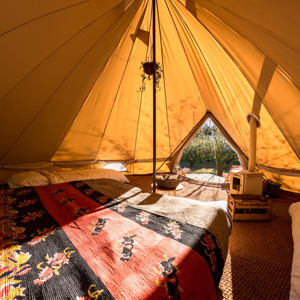 Tweepersoons bed en witte houtkachel