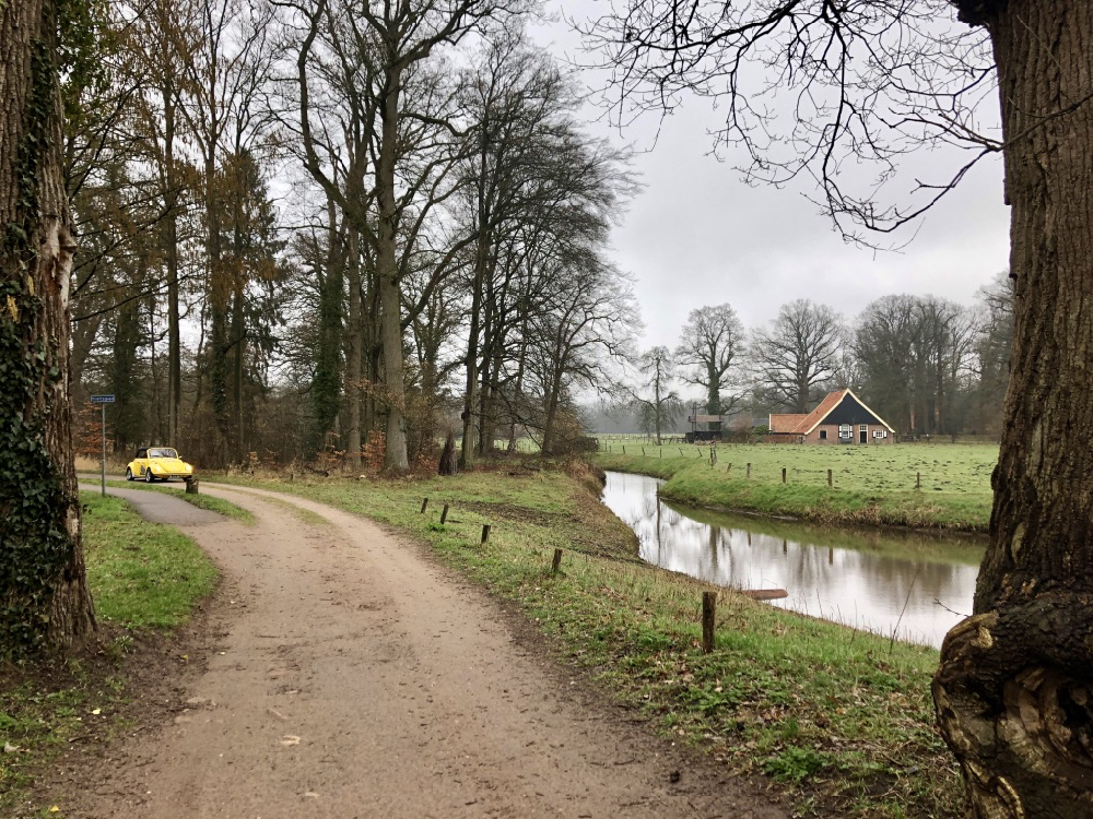 Een gele Volkswagen Kever op een landweg bij Watermolen Noordmolen op Landgoed Twickel