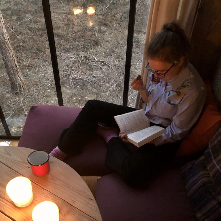 Hoekje op de bank waar meisje een boek leest