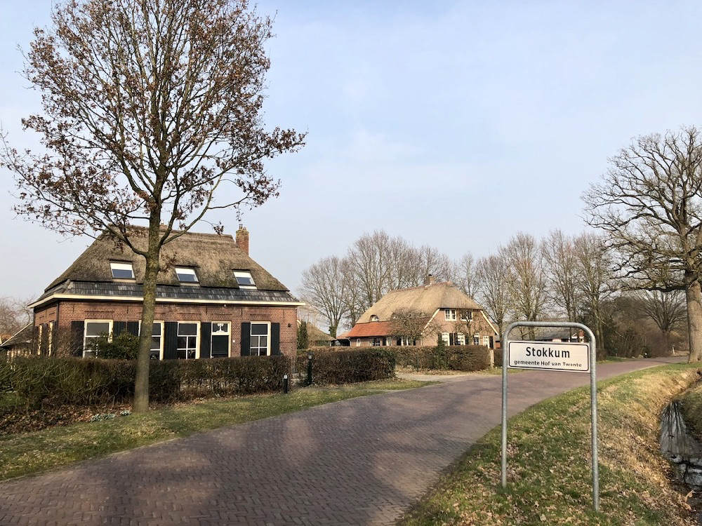Twee boerderijen aan een weg met naambordje Stokkum