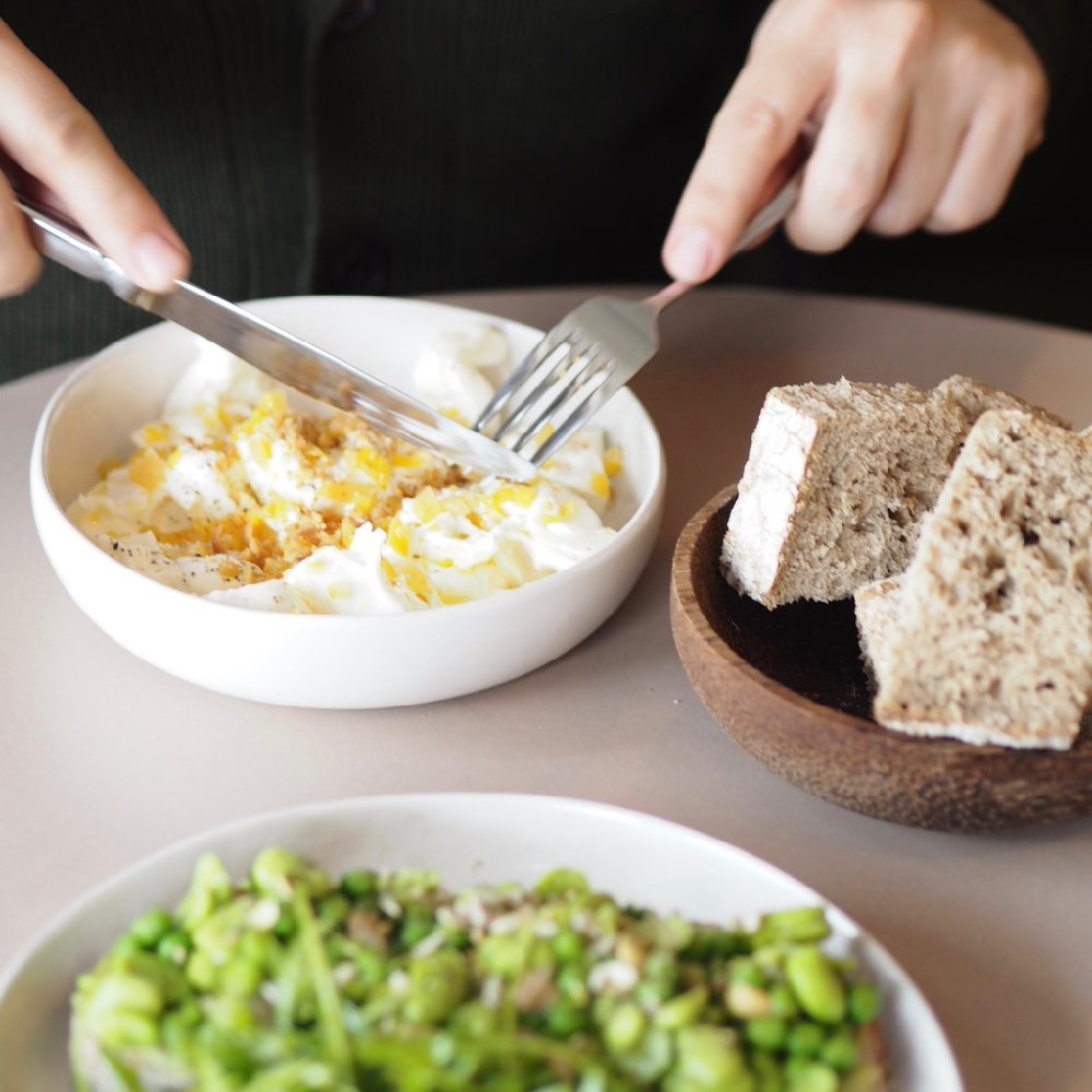 Een scrambled egg in een wit bord met brood ernaast