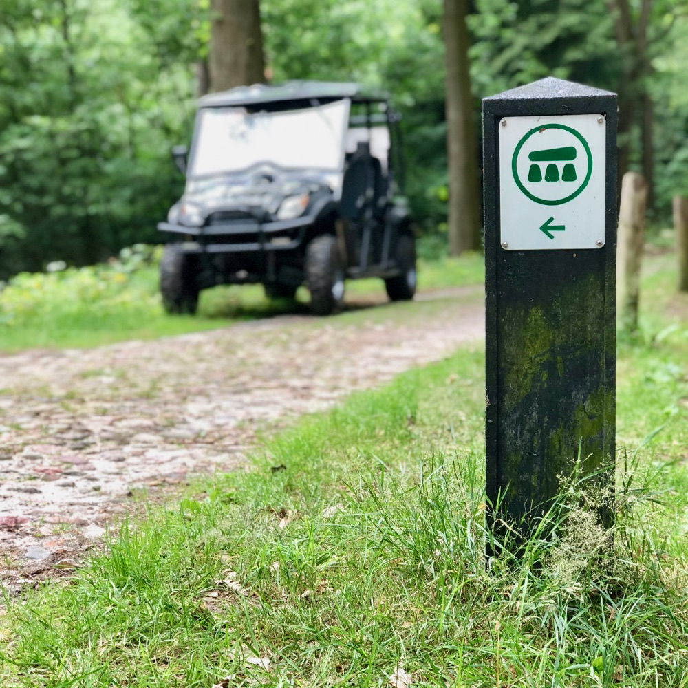 Terreinwagen naast een paaltje met richtingaanwijzer voor Hunebedden