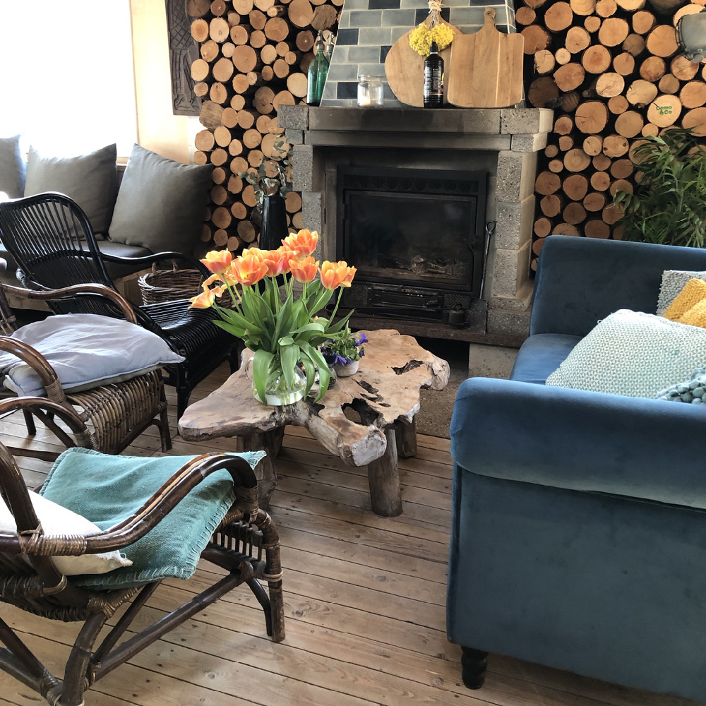 Gezellig zitje met rotan stoelen en blauwe fluwelen bank bij de haard