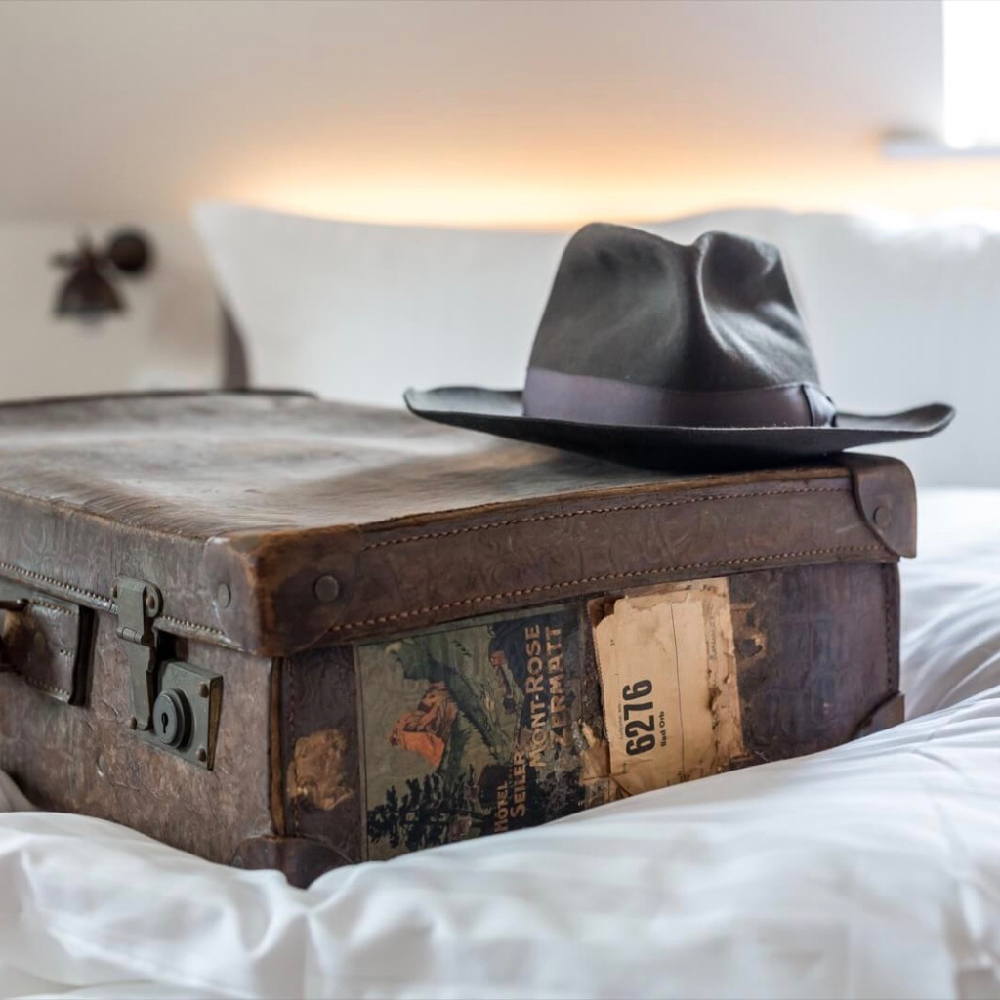 Vintage koffer met hoed op een hotelbed