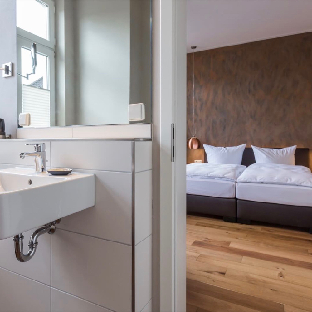 Doorkijkje vanaf een badkamer naar het bed in een hotelkamer