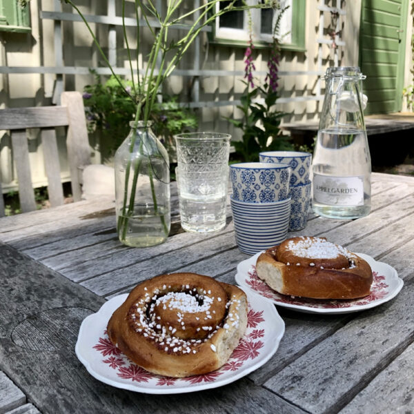 Kaneelbroodjes met glazen water op tafel in de tuin