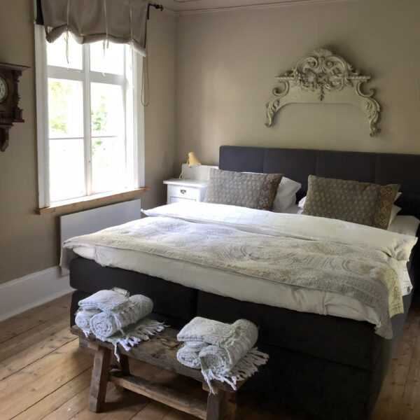 Tweepersoons bed met houten bankje met handdoeken