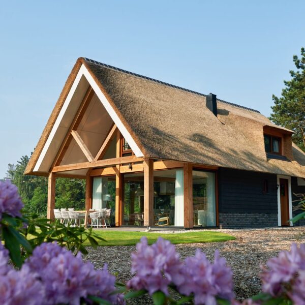 Rietgedekte luxe vakantievilla met rododendrons ervoor