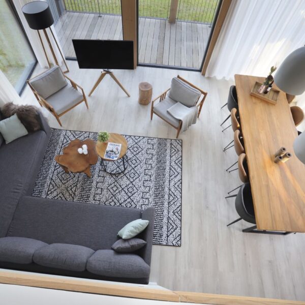 Woonkamer vanaf boven gezien, met grijze hoekbank en lange eettafel