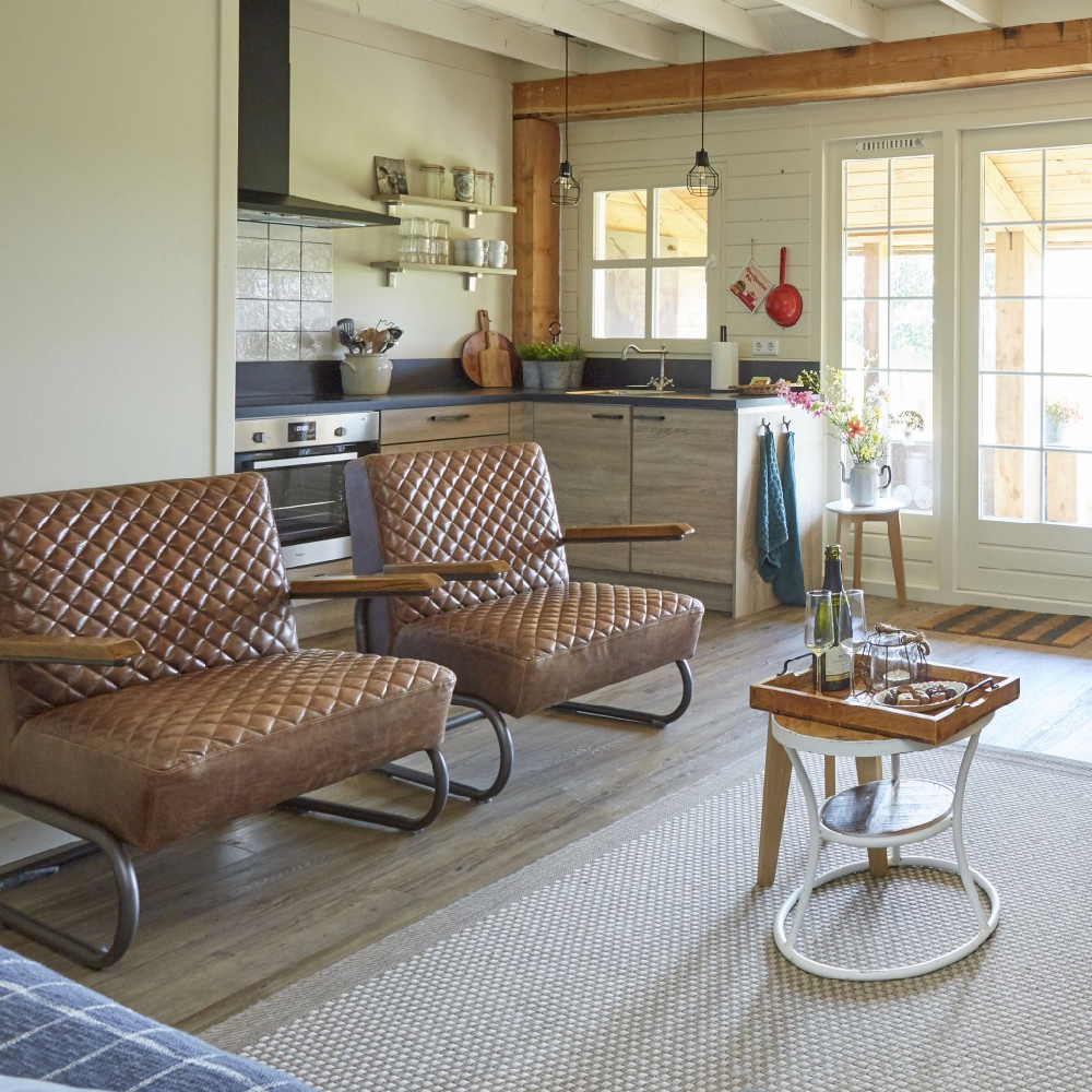 Woonkamer met twee bruine leren fauteuils en zicht op de keuken