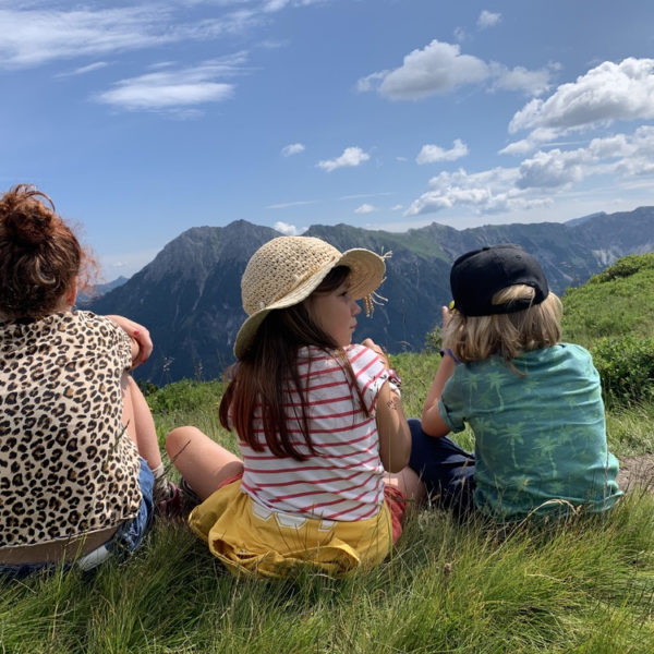 Drie kinderen in het gras tijdens een vakantie in Oostenrijk