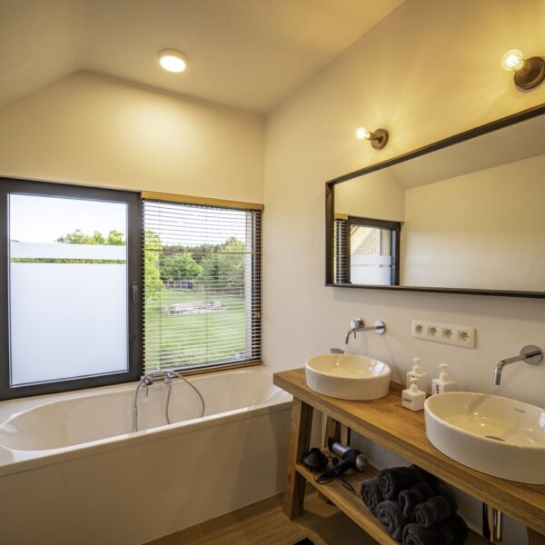 Badkamer met bad en twee wastafels
