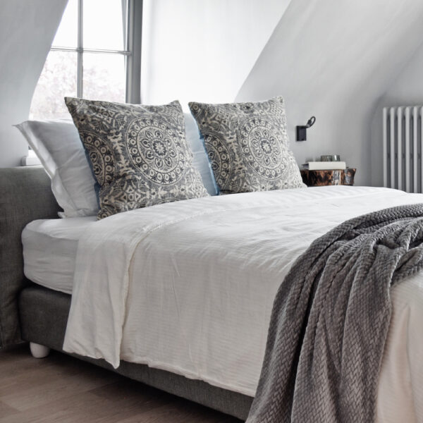 Lichte luxe bed and breakfast kamer met grijze sprei en zacht bedlinnen