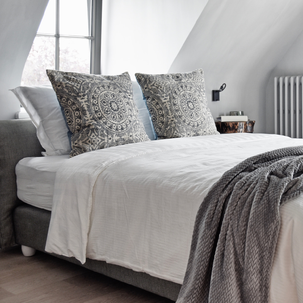 Lichte luxe bed and breakfast kamer met grijze sprei en zacht bedlinnen