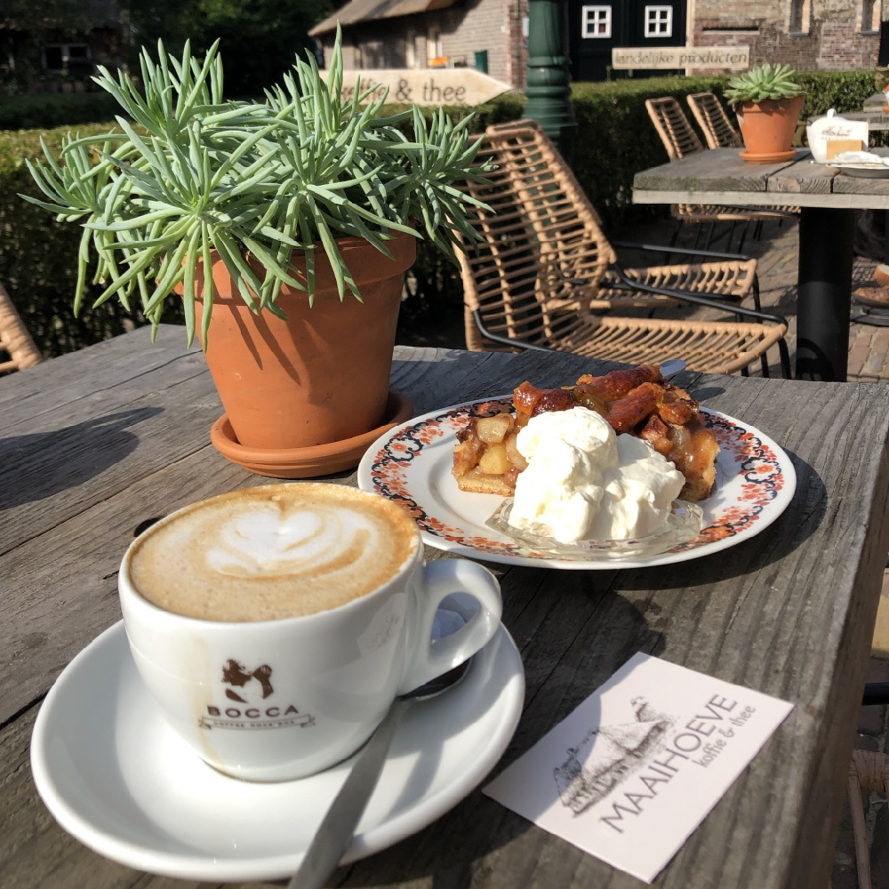 Een kopje koffie met taart op een houten tafel op het terras