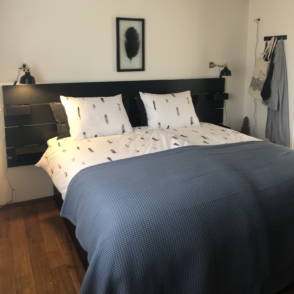 Slaapkamer met tweepersoons bed, met blauwe sprei en veren dekbed