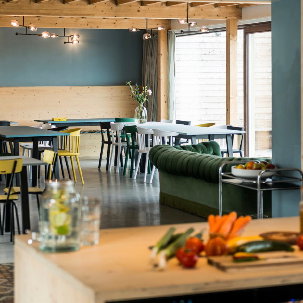 Lichte eetkamer met blauwe wand met meerdere tafels en gekleurde stoelen