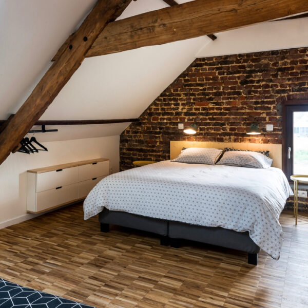 Slaapkamer met stoere balken en een tweepersoons bed