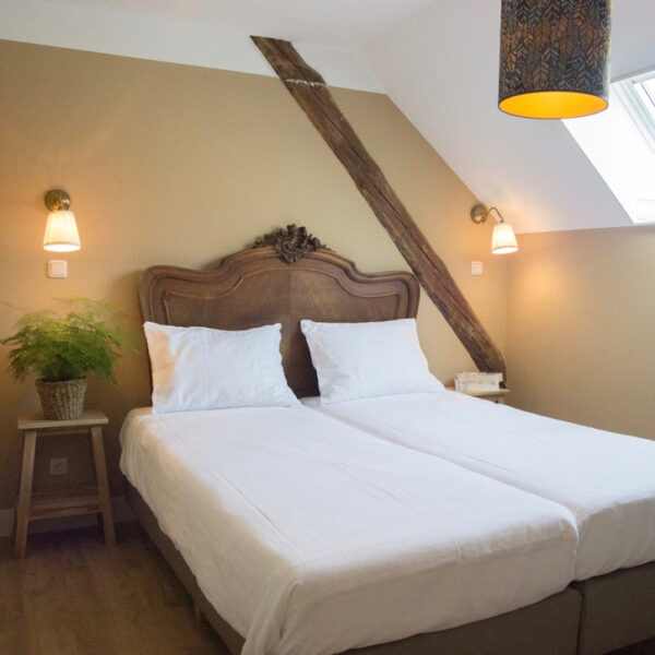 Slaapkamer met opgemaakt bed met antiek hoofdeinde