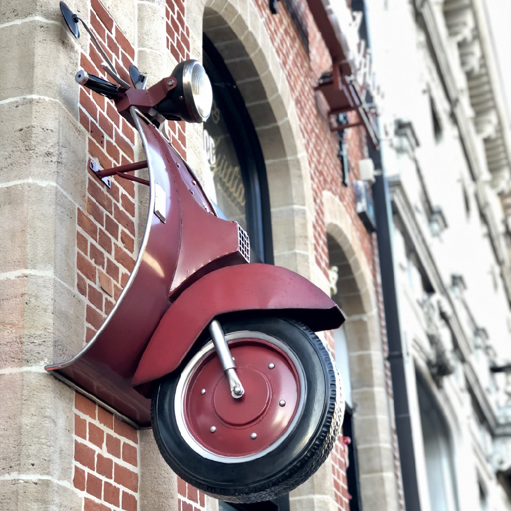 Rode vintage scooter aan de buitenwand van het hotel